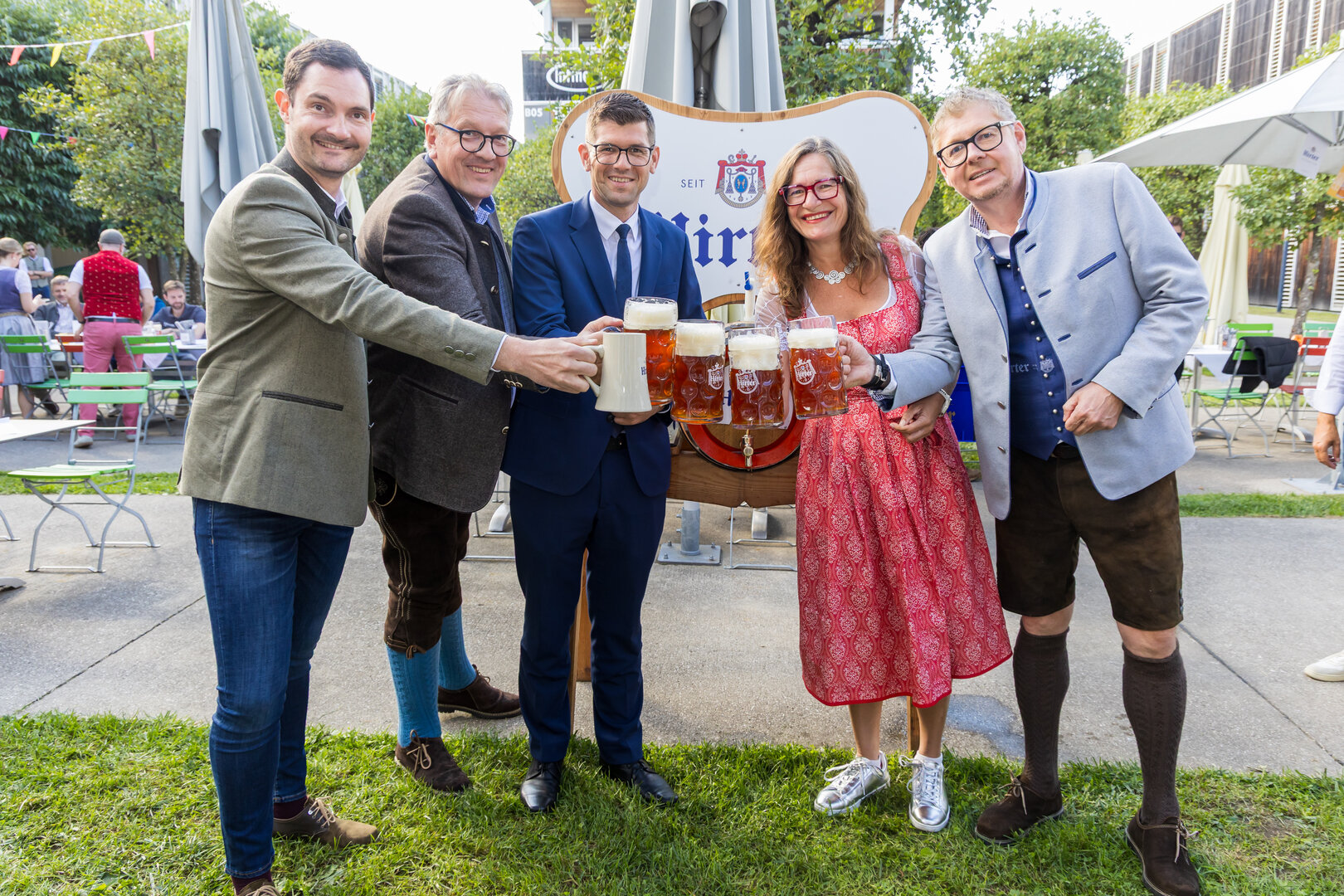Fünf Personen mit Bierkrügen vor einem Bierfass-Schild in Wien